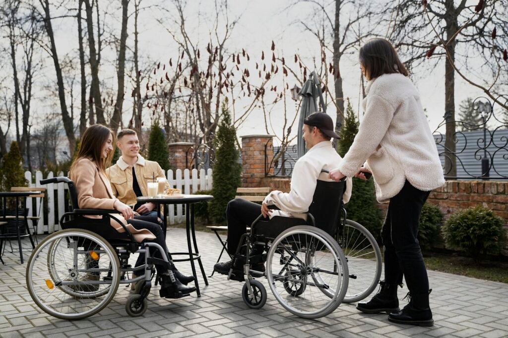 A group of friends, two using wheelchairs, meeting at an outdoor café table